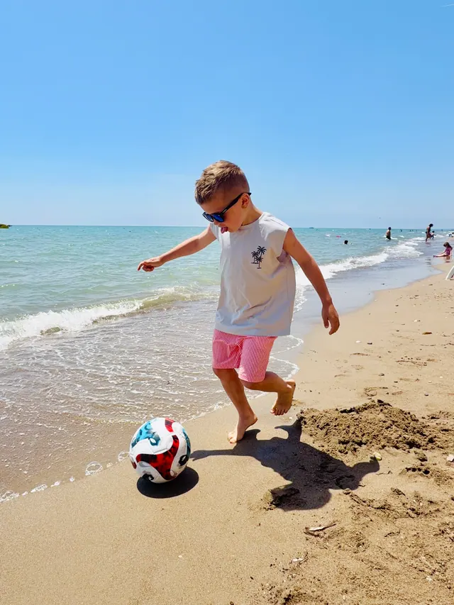 Joshua kicking a ball on the beach